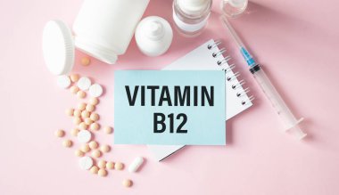 İçinde hap, kalem, tıbbi konsept ve üst görünüm olan bir masanın üzerinde VITAMIN B12 yazılı defter sayfası.
