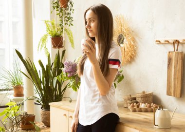 Genç ve mutlu bir kadın sabahları mutfakta kahve içiyor..