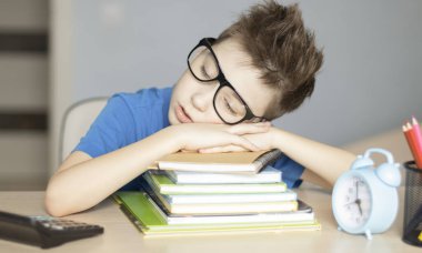 Genç adam masada kitaplarla uyuyor.