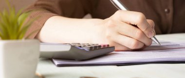 Kadınların elleri hesap makinesine güvenir ve formu doldurur..