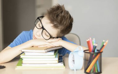 Genç adam masada kitaplarla uyuyor.