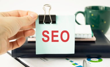 İş adamının elinde SEO SEARCH SEGINE optimizasyonu yazılı bir kart tutmasına yakın plan, yumuşak odaklı iş konsepti imajı ve klasik ton