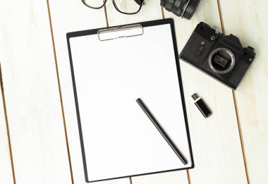 Tasarımcı bürosunun masasında beyaz boş kağıtlar. Temiz bir masaüstünde eski bir kamera ve işaret var. Uzayı kopyala.