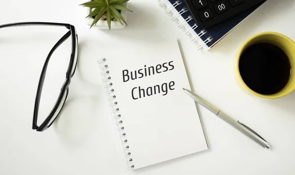 Business Change text on Notebook with pen, glasses and a cup of coffee