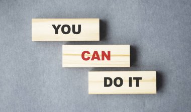 Gri arka planda tahta bloklar üzerine yazabilirsin. Motivasyon, kişisel başarı kavramı için teşvik edici kelimeler.