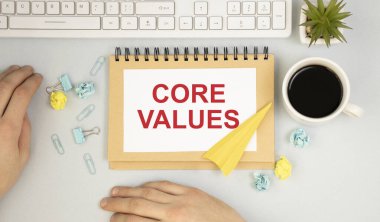 Core Values içinde metin ile defter masada kahve, dizüstü bilgisayar ve çizelgeler ve diyagramlar ile bazı kağıtlar