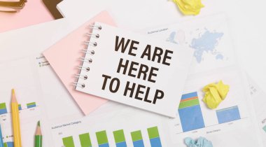 Yardım etmek için buradayız, bir not defterine, ofis masasında, aksesuarlarla birlikte..