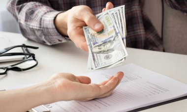 Genç adam elinde bir dolar saydı, mali hesap yönetimi ve ödeme veya tasarruf kavramı.