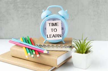 Kitapların arkaplanındaki mavi alarmlı saati öğrenme zamanı. Eğitim konsepti. Dersleri öğrenme zamanı..