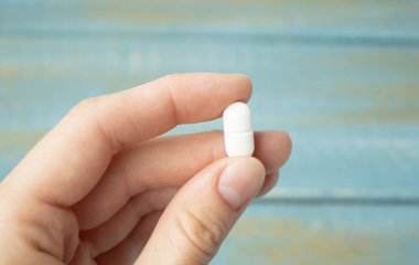 Beyaz tablet ahşap arka planda, yakın plan. Sağlık kavramı.