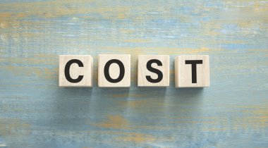 Tahta blokta yazılmış bir kelime. desing, konsept için çimento masadaki maliyet metni.