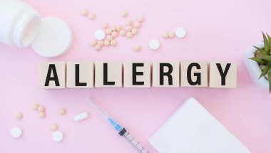 Tahta bloklardaki ALLERGY metni. Bir sıra küpün önünde arka planda ampuller var - tabletlerden çıkan beyaz plastik ambalajlar. Resmi Kabul Et.