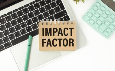 Üzerinde IMPACT FACTOR yazan bir kart tutan bir iş adamı. Klavye, hesap makinesi ve beyaz arkaplan