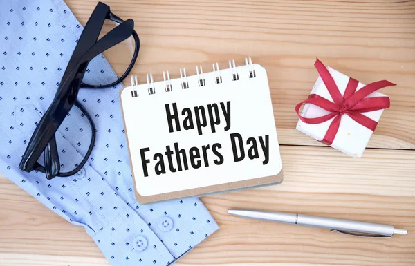 Happy fathers day sign on paper and colorful tie laid on wooden floor backround.