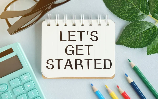 LET\'S GET STARTED text concept write on notebook with office tools on blue background