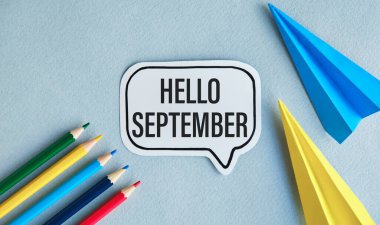 written hello september text on notepad with pencils on table