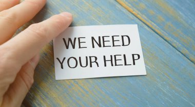 İş kadını elinde yazılı bir kart tutuyor. Yardımına ihtiyacımız var. İş konsepti