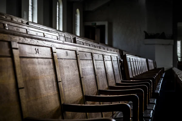 Rows of wooden pews in a closed down building — Stock Photo, Image