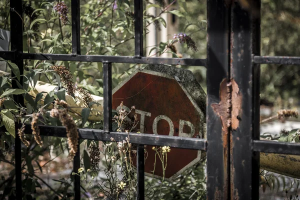 Sinal de parada em decomposição atrás do portão metálico enferrujado — Fotografia de Stock