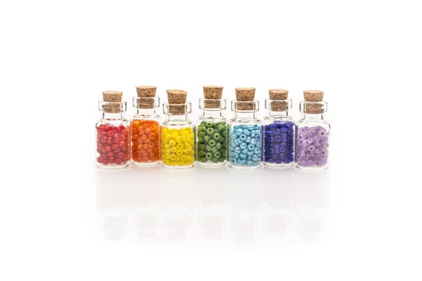 Perline arcobaleno in piccole bottiglie di vetro Fotografia Stock