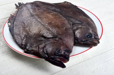 Beyaz tabakta iki taze pisi balığı ve beyaz ahşap arka plan. Boşluğu kopyala