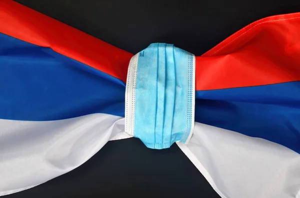 Flag of russia tied with a face protection mask. COVID - 19 problems in Russia and in the world. Medicine, healthcare and virus concept. black background