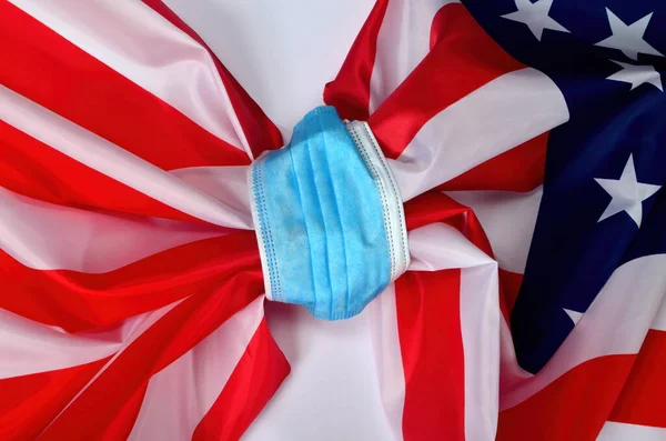 Flag of USA tied with a face protection mask. COVID - 19 problems in United States and in the world. Medicine, healthcare and virus concept. white background