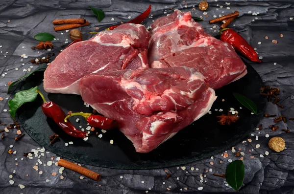 Siyah taş arka planda baharatlı taze çiğ koyun eti. Büyük parça shmeat fileto ya da fileto yakın çekim