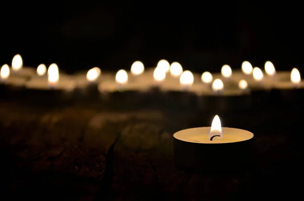 Karanlıkta yanan bir sürü küçük noel mumu. Sığ alan derinliği, seçici odak