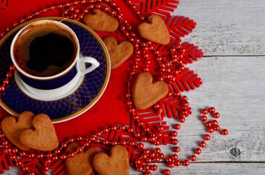 Kahve fincanı, masada zencefilli kurabiye ve Noel süslemeleri.