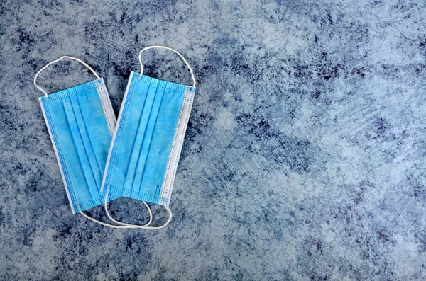 Many medical face masks on the blue stone background, flat lay. Medical protective mask isolated on blue background. Prevent coronavirus covid - 19