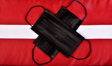 Black face protection mask on the Latvian flag. Covid - 19 epidemic and virus protection concept. Problems of coronavirus pandemic in Latvia clipart