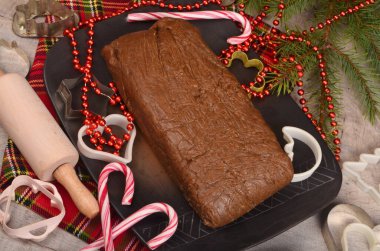 Koyu kil tabakta çiğ zencefilli hamur parçaları, Noel süslemeleri, hamur ruloları ve kesiciler. Noel kurabiyelerini hazırlayın.