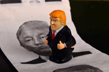 Riga, Letonya - 07 Ocak 2021: Pantolonu aşağıda Trump 'ın resmiyle tuvalet kağıdının üzerinde duran küçük Donald Trump figürü