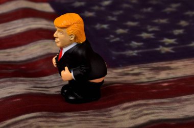 RIGA, LATVIA - JANUARY 07, 2021: Pantolonlu küçük Donald Trump figürü klasik ABD bayrak sahasında duruyor