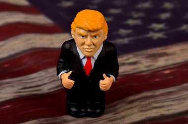 RIGA, LATVIA - HAZİRAN 07, 2021: Eski ABD bayrağı üzerinde duran küçük Donald Trump figürü