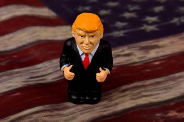 RIGA, LATVIA - HAZİRAN 07, 2021: Eski ABD bayrağı üzerinde duran küçük Donald Trump figürü
