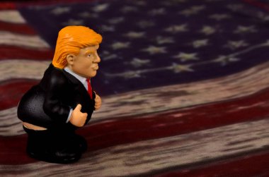 RIGA, LATVIA - JANUARY 07, 2021: Pantolonlu küçük Donald Trump figürü klasik ABD bayrak sahasında duruyor