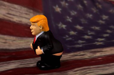 RIGA, LATVIA - JANUARY 07, 2021: Pantolonlu küçük Donald Trump figürü klasik ABD bayrak sahasında duruyor
