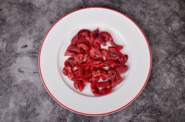 Çiğ et ince şeritler halinde kesilmiş beyaz tabakta Stroganoff bifteği için.