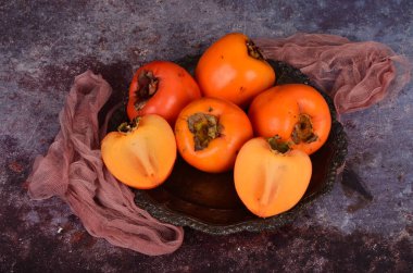 Bir grup olgun portakal meyvesi. Tabakta hurma meyvesi, kırsal arka plan, Hurma meyvesi.