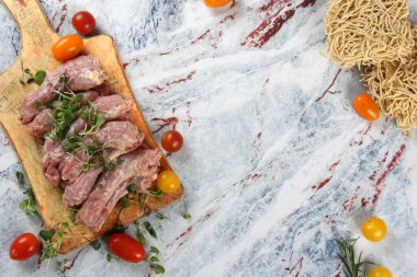 Çiğ tavuk boynu, domates, yeşillik ve yumurta eriştesi açık mermer arka planda, kopyalama alanı