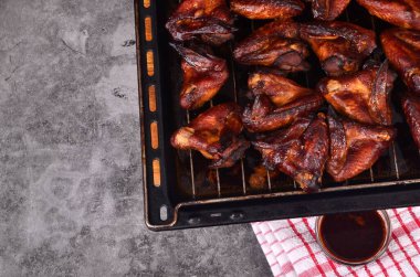 Fırın tepsisinde ızgara tavuk kanadı. Fırında kızartılmış çıtır çıtır ballı tavuk kanatları, üst manzara.