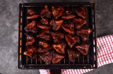 Fırın tepsisinde ızgara tavuk kanadı. Fırında kızartılmış çıtır çıtır ballı tavuk kanatları, üst manzara.