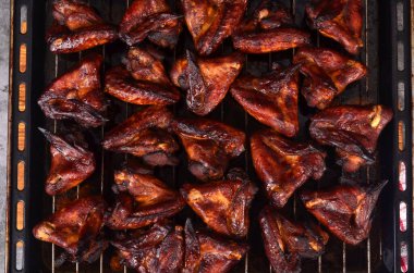 Fırın tepsisinde ızgara tavuk kanadı. Fırında kızartılmış çıtır çıtır ballı tavuk kanatları, üst manzara.