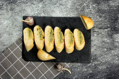 Siyah bir tabakta ev yapımı sarımsaklı ekmek. Koyu arkaplan