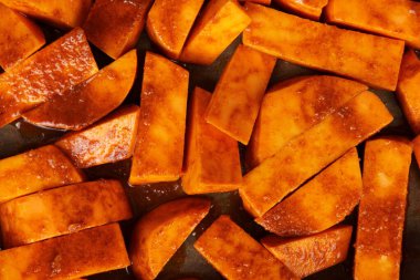 Fırın tepsisinde yağlı ve baharatlı dilimlenmiş çiğ patates. Fırında tatlı patates ya da batata tarifi pişirmek.