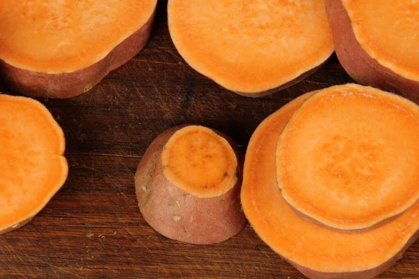 stock image Sliced sweet potato on wooden board background, close up. Raw sweet potatoes or batatas