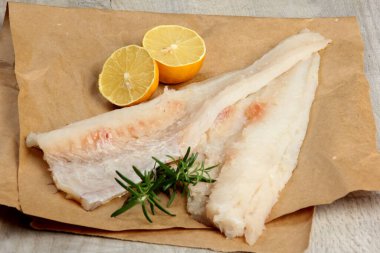 Limon ve biberiyeyle süslenmiş iki parça balık fileto, derisi olmayan beyaz çiğ balık fileto.