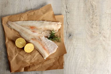 Limon ve biberiyeyle süslenmiş iki parça balık fileto, derisi olmayan beyaz çiğ balık fileto.